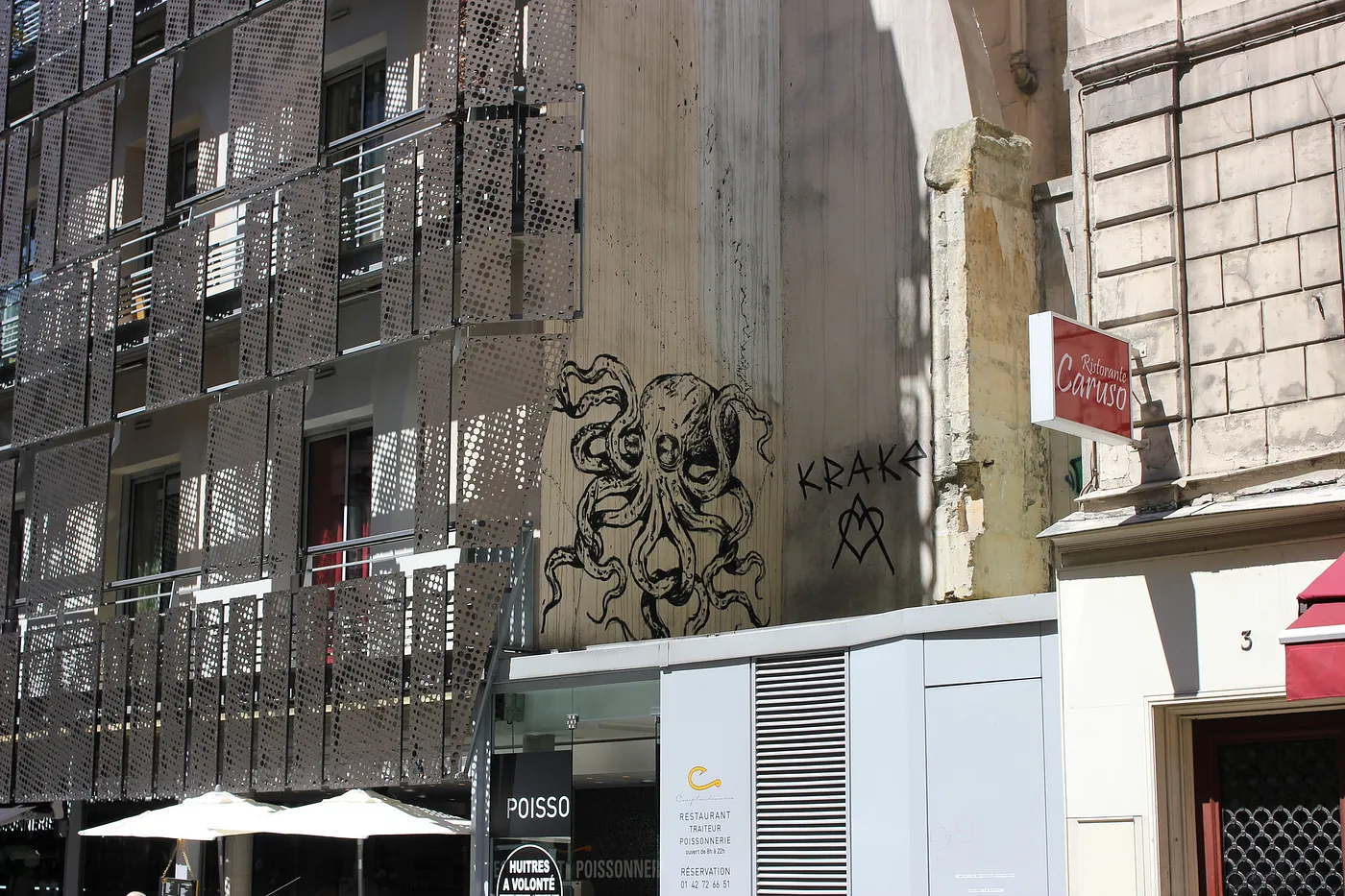 Auto-generated description: A detailed octopus mural is painted on the side of a building with urban architecture and various signs around it.