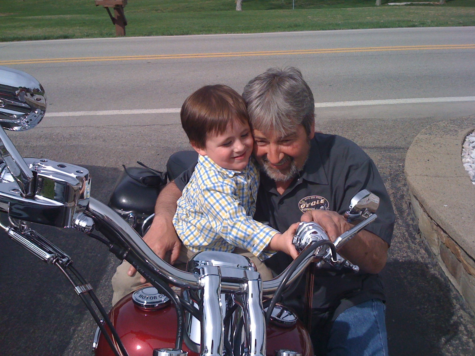 A man and a child are smiling together on a motorcycle.